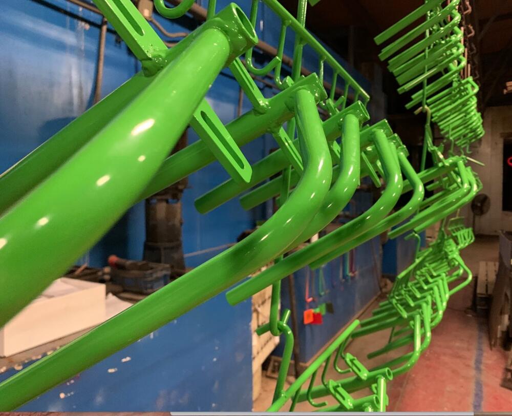 Freshly powder-coated green tube parts hanging on the line in the Bushnell shop